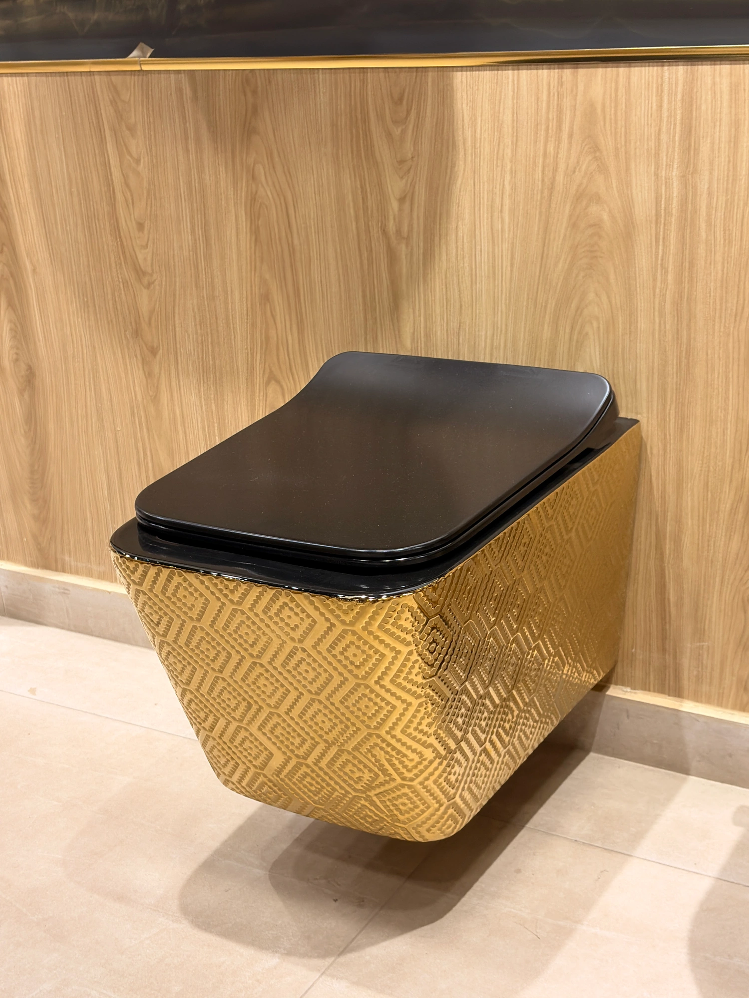 Wall-hung toilet with bidet spray and gold-finish shut-off valve.